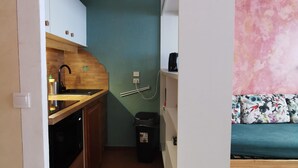 Une cuisine de taille réduite, avec des meubles de rangement en bois, un évier et une poubelle.
