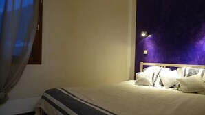 Une chambre à coucher avec un lit, une fenêtre avec des rideaux et un mur orné d’une fresque violette.