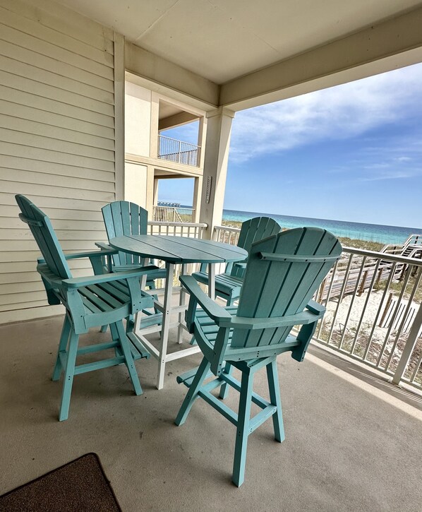 A covered outdoor seating area with a table and chairs, overlooking a beach.