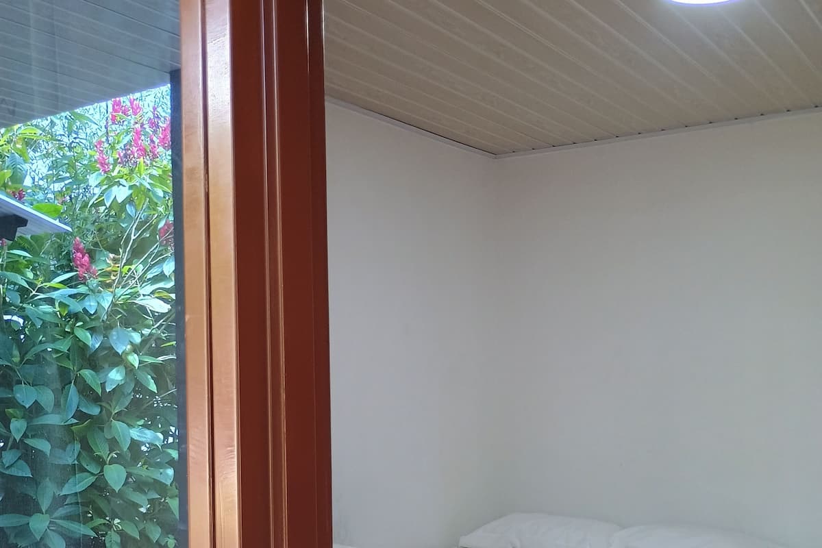 A bedroom with a bed, a window, and a ceiling light.