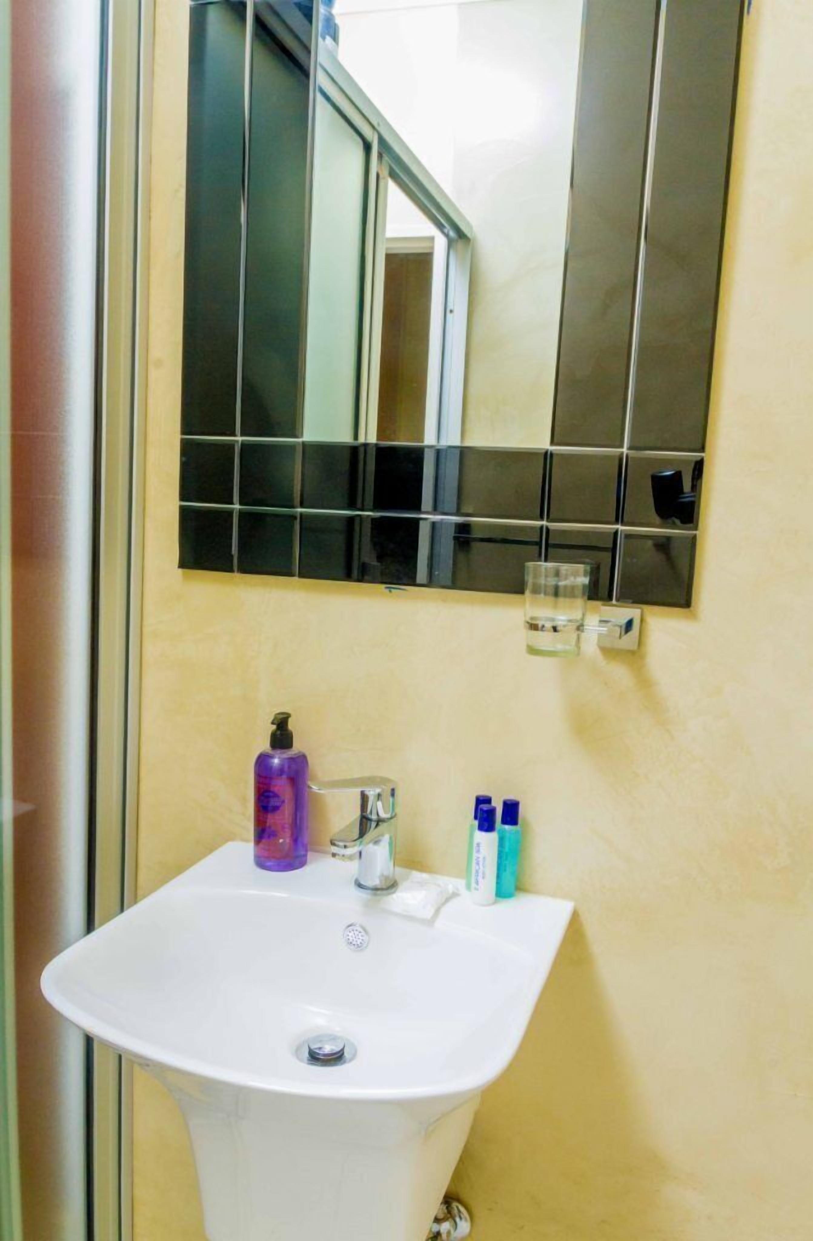 A bathroom with a white sink, a mirror, and toiletries.