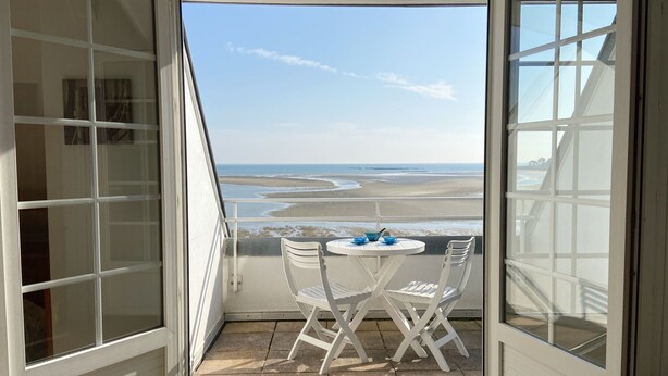 A balcony with a table and chairs, overlooking a beach with waves and a clear sky. - MOUETTES 3 - Apartment with sea view between Carnac and Trinité-sur-Mer - T356 (La Trinité-sur-Mer)