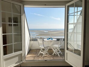 A balcony with a table and chairs, overlooking a beach with waves and a clear sky. - MOUETTES 3 - Apartment with sea view between Carnac and Trinité-sur-Mer - T356 (La Trinité-sur-Mer)