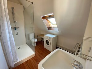 A compact bathroom with a shower, toilet, washing machine, and a small window. - MOUETTES 3 - Apartment with sea view between Carnac and Trinité-sur-Mer - T356 (La Trinité-sur-Mer)