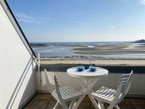 A balcony with a white table and chairs, overlooking a beach with sand and water. - MOUETTES 3 - Apartment with sea view between Carnac and Trinité-sur-Mer - T356 (La Trinité-sur-Mer)