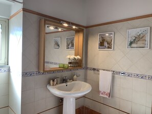 Un baño con un lavabo blanco, un espejo y azulejos decorativos.