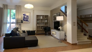 Una sala de estar moderna con un sofá, un televisor y una escalera.