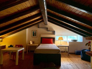 Un dormitorio acogedor en el ático con cama, escritorio y ventana.