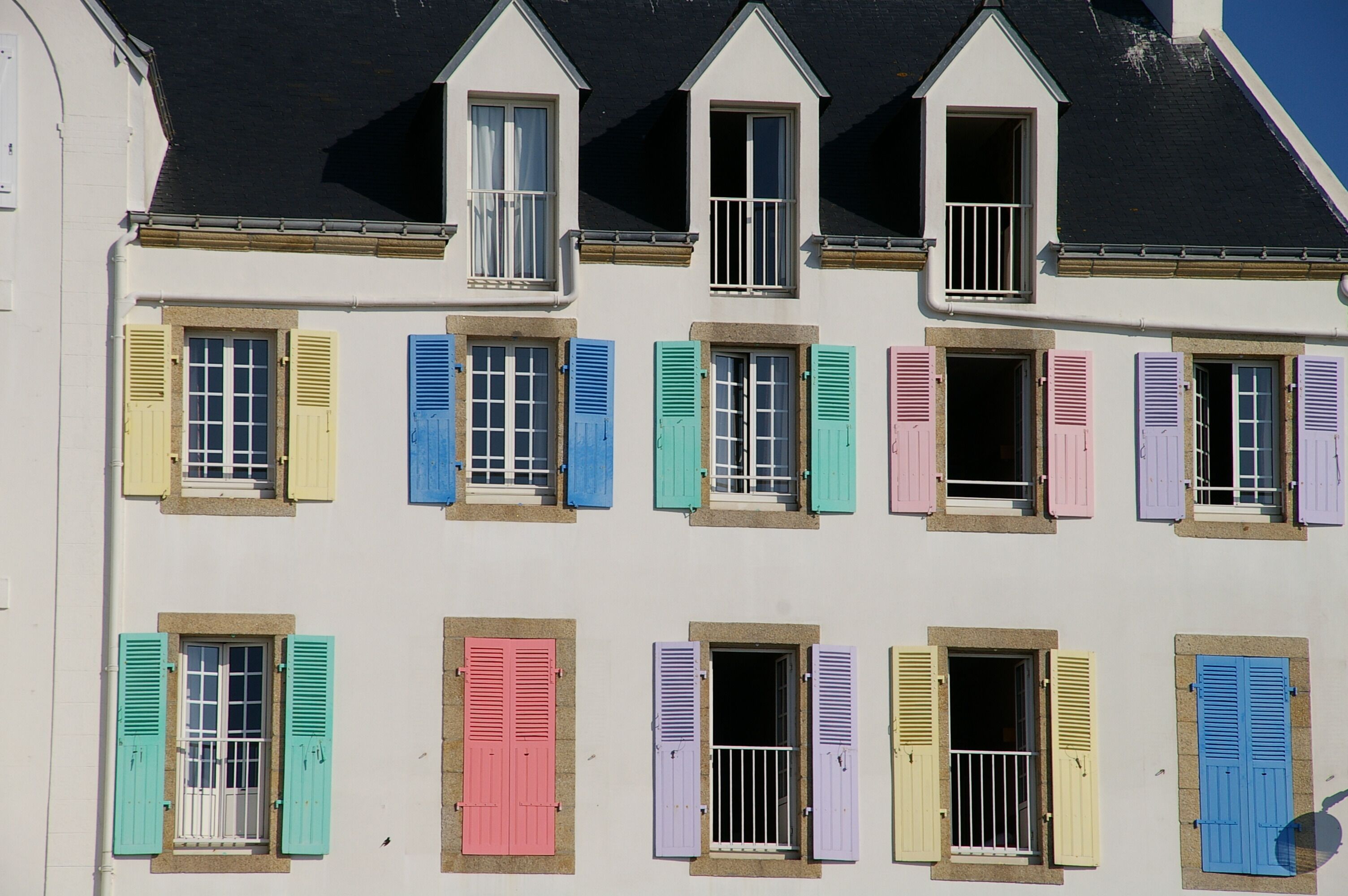A row of colorful shutters on a building's facade.