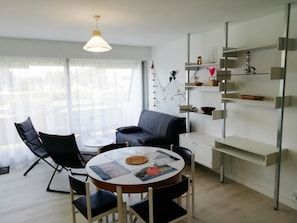 Un soggiorno moderno con un tavolo rotondo, due poltrone, una divano e una mensola decorativa a parete.