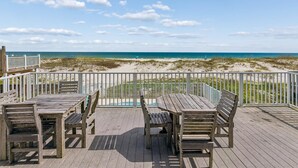 Eine Holzterrasse mit Blick auf Strand und Meer.