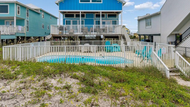 Ein Strandgrundstück mit Pool, einem Balkon und einer Treppe, die zu der oberen Etage führt.