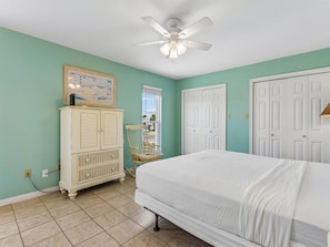 Une chambre à coucher avec un lit, un ventilateur de plafond, une commode et une fenêtre.