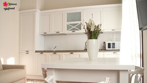 A modern kitchen with white cabinetry, a white island, and a vase with flowers. - Hibiscus apartment | Garda Lake & Golf (Padenghe Sul Garda)