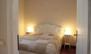 Ein Schlafzimmer mit einem Bett, zwei Nachttischen mit Lampen und einer Tür.
