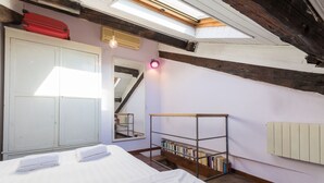 Een slaapkamer met een bed, een kledingkast, een boekenkast en een dakraam.