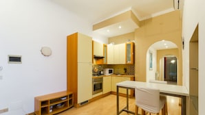 Una cucina compatta con mobili in legno, un forno a microonde e un'area pranzo con tavolo e sedie.