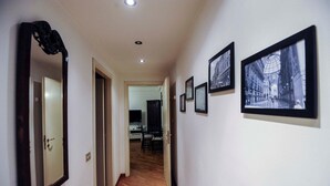 A hallway with framed pictures on the walls, a wooden floor, and a door leading to a room. - Park Apartment (Milan)