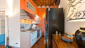 Una cocina compacta con electrodomésticos modernos, techo de madera y salpicadero de azulejos.