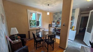 A compact living space with a dining area, kitchenette, and a small seating area with a sofa and chairs. - Bienvenu Chez Lisette (Les Ollières-sur-Eyrieux)