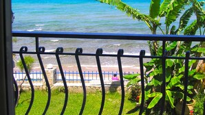 Un balcon avec vue sur l’océan et une clôture bleue.