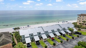 A coastal hotel with a beach view, multiple parking spaces, and a row of buildings with a flat roof. - Stunning Gulf Front Townhouse! Private beach, beach chairs, wagon, and cooler! (Santa Rosa Beach)