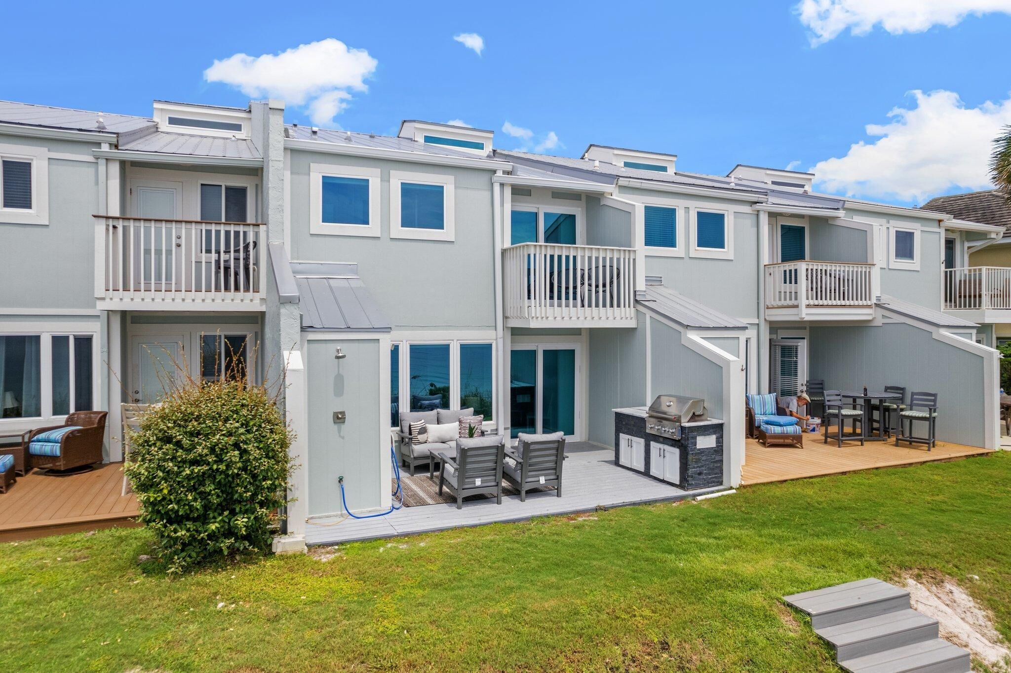 A multi-story residential building with balconies, a deck, and outdoor seating area.