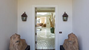 En hall med ett klinkergolv som leder in till ett rum med en soffa och en lampa.