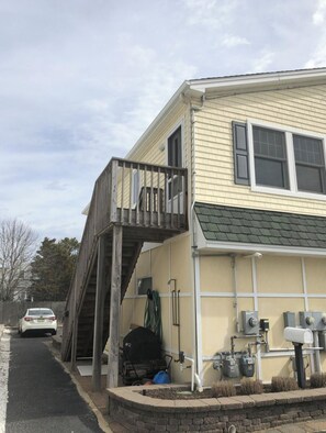 A two-story house with a balcony, a garage, and outdoor utility equipment.