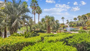 A lush garden with palm trees, a fountain, and a pool. - Enjoy Comfort & Peace w/ Balcony and Amenities (Hilton Head Island)