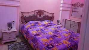 A bedroom with a bed, nightstand, dresser, and a mirror.