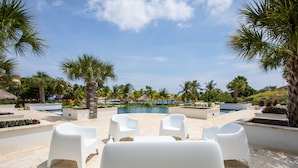 A poolside area with white plastic chairs and palm trees.