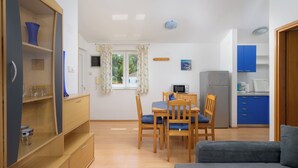 A compact living space with a dining area, kitchenette, and a sofa. - Charming Apartment with Garden - beach 300 m away (Vinkuran)