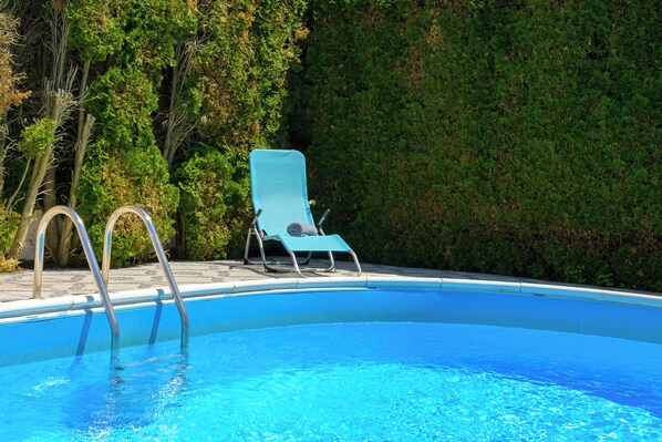 Ein Swimmingpool mit blauem Stuhl und Metallleiter.