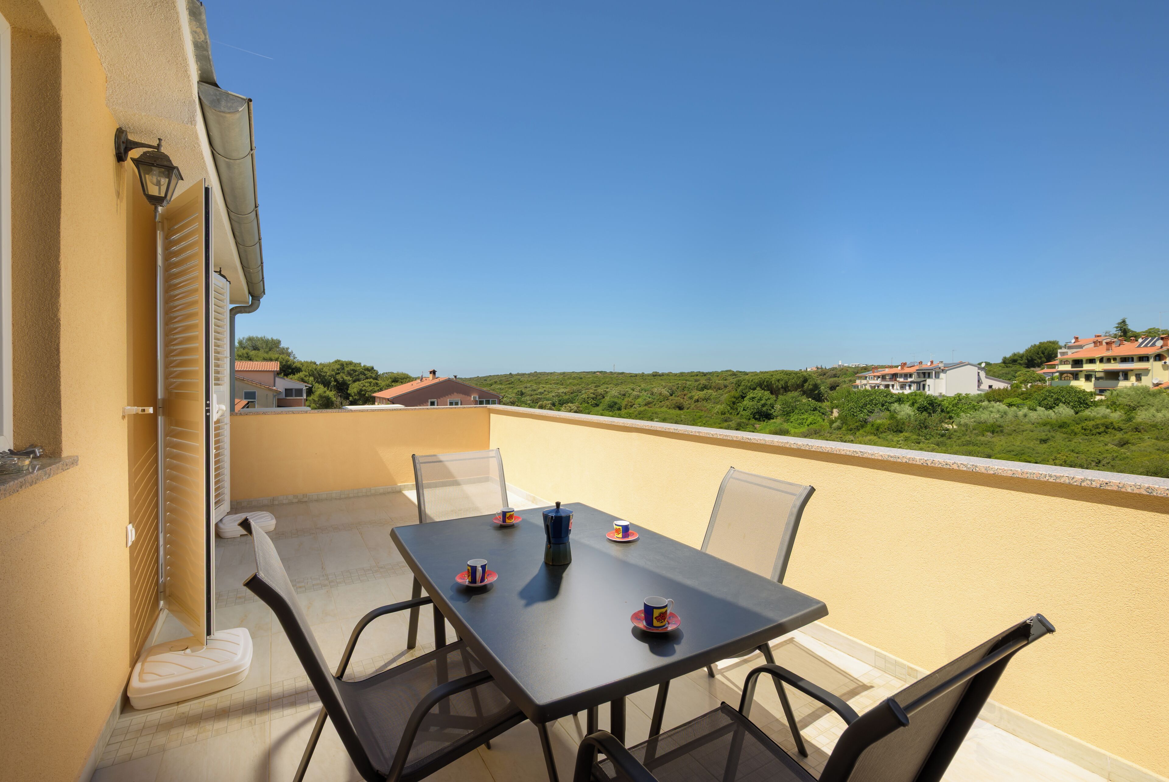 Ein Balkon mit Tisch, Stühlen und Blick auf die Landschaft.