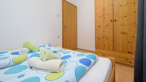 A bedroom with a bed, a wooden wardrobe, and a door. - Charming Apartment with Garden - beach 300 m away (Vinkuran)