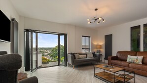 A modern living room with a sofa, a coffee table, and a view through large glass doors. - No3 Highpoint luxury townhouse, 2en-suite bedrooms onsite indoor swimming pool  (Saundersfoot)