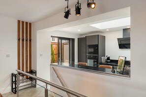 Una cocina moderna con una isla grande, electrodomésticos integrados y un separador de vidrio.