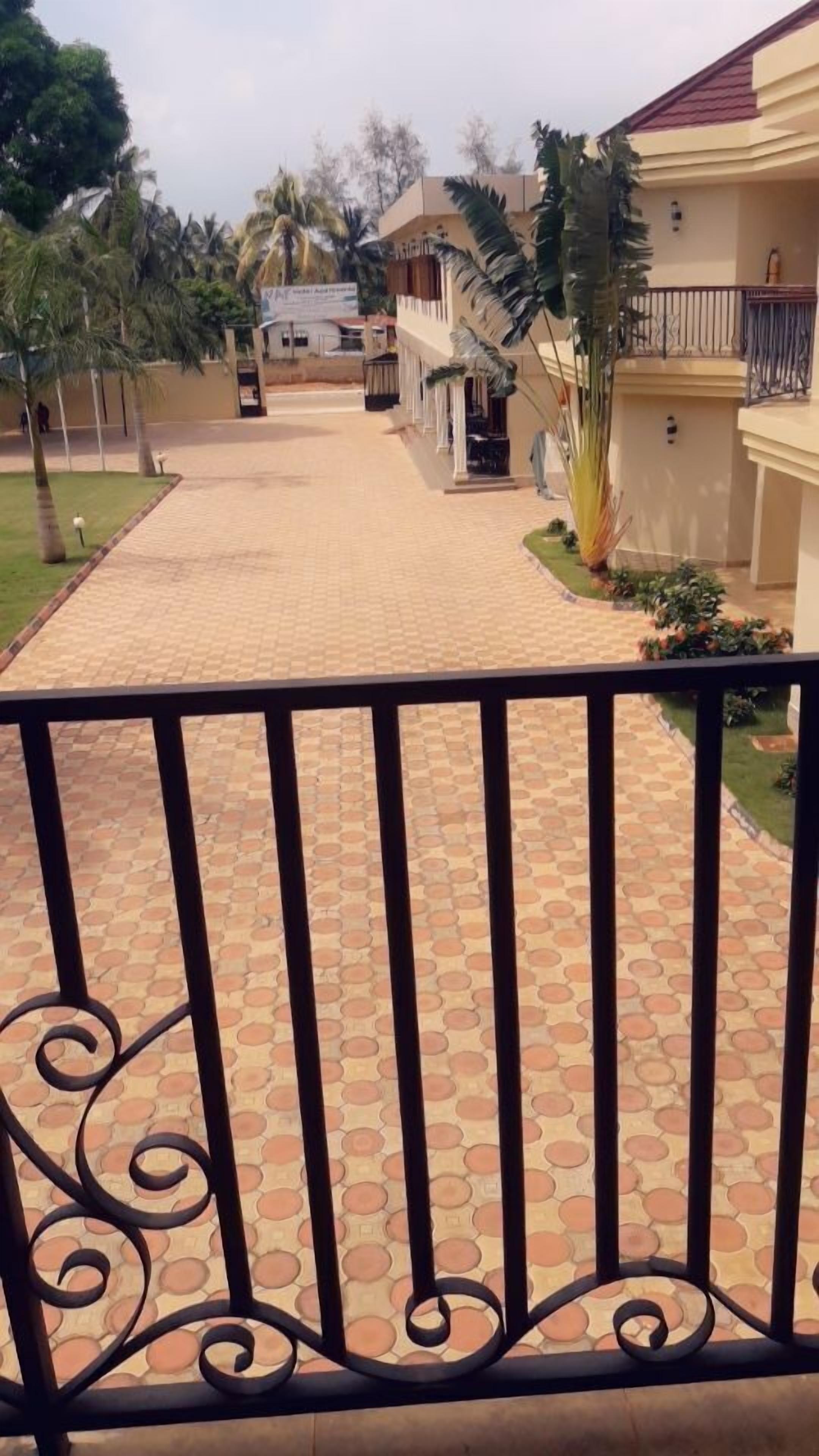 A paved walkway leading to a building with a balcony.