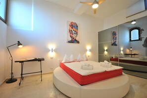A modern bedroom with a bed, a desk, and a large mirror.
