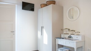 Ein helles Badezimmer mit Einbauschrank, Waschtisch und Spiegel sowie einem Fernseher, der über dem Schrank angebracht ist.