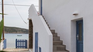 Ein weißes Gebäude mit blauen Fensterläden und einer Steintreppe, die zu einer Tür führt.