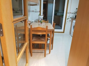 A dining area with a wooden table and chairs, a window with a view of the kitchen, and a sliding glass door leading to another room. - Anjelus apartment in Mutriku (Mutriku)