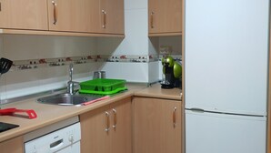 A kitchen with wooden cabinets, a Bosch dishwasher, a white refrigerator, and a green dish rack. - Anjelus apartment in Mutriku (Mutriku)