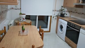 A compact kitchen with a dining table, a built-in washing machine, and a stove. - Anjelus apartment in Mutriku (Mutriku)