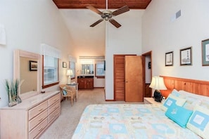Ein Schlafzimmer mit Bett, Kommode, Schminktisch und Deckenventilator.
