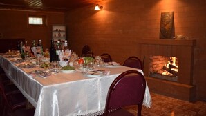 A long dining table set for a meal with a fireplace in the background. - Guesthouse Lago & Wine Cellar (Lagodekhi)