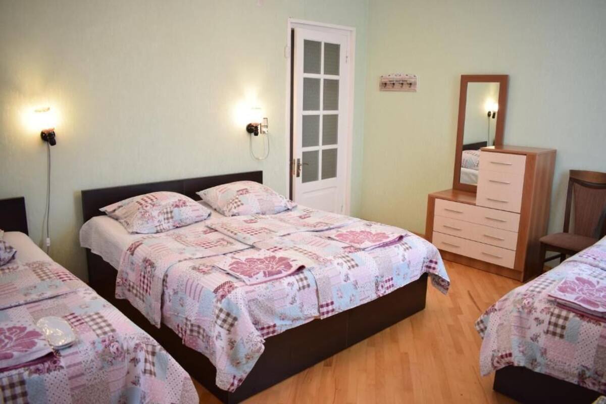 A bedroom with two beds, a dresser, a mirror, and wall-mounted lights.