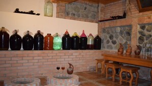 A rustic interior with brick walls, a stone fireplace, and a shelf with various containers. - Guesthouse Lago & Wine Cellar (Lagodekhi)
