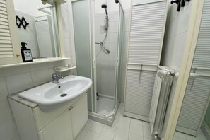 A bathroom with a white sink, mirror, shower, and radiator. - Nonna Rosetta Traditional Studio (Vernazza)